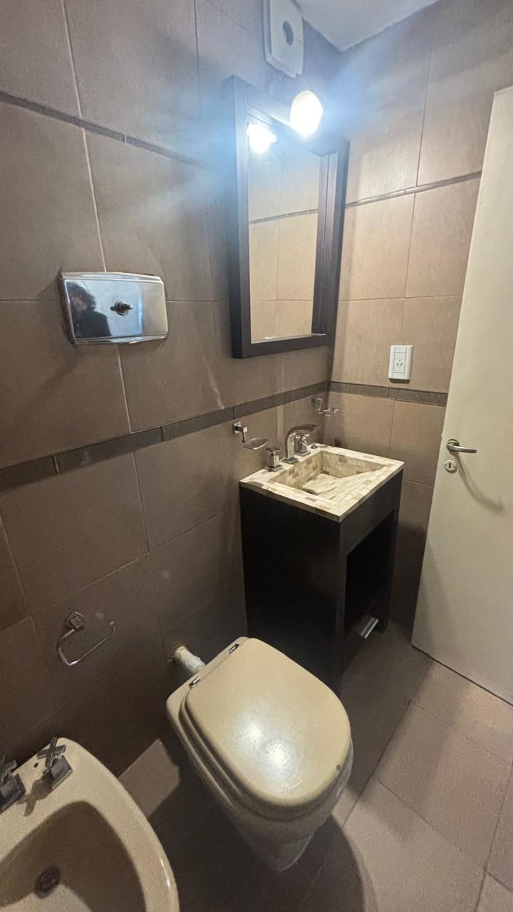 Baño con lavatorio sobre mueble, espejo con luces e inodoro