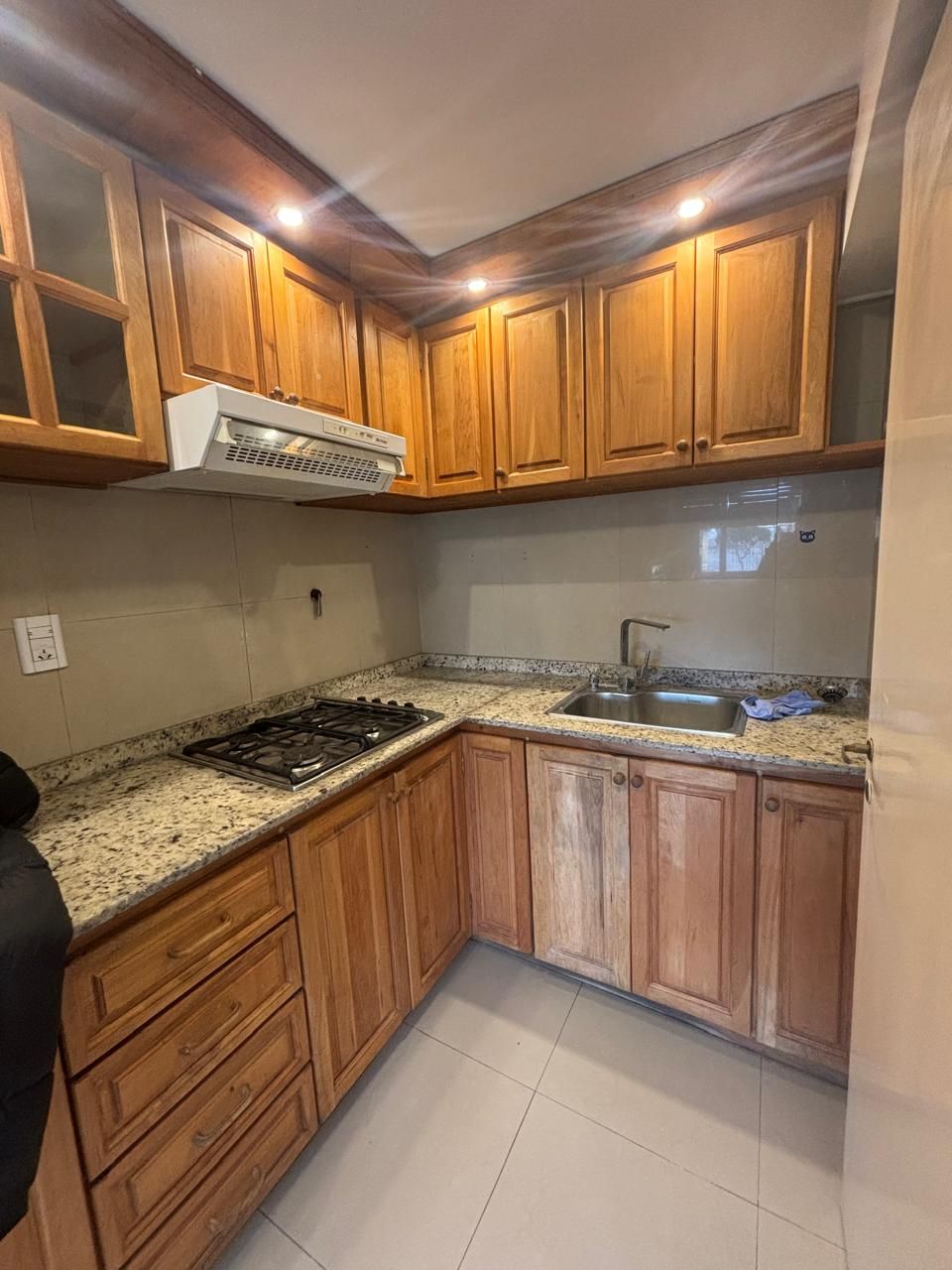 Cocina en L con anafe, bacha de acero y alacenas de madera